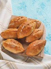 Delicious pies on the blue table. Small pies with cabbage. Homemade cake.