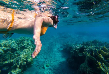 Foto op Canvas Woman snorkeling above coral reef © salajean