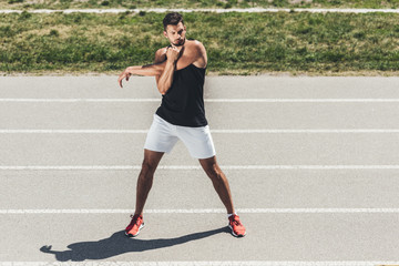 Fototapeta na wymiar male athlete stretching on running track at sport playground