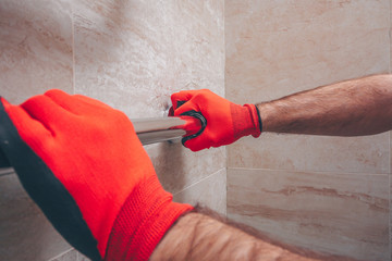 Working plumber tightens the fitting nut of an American type by mounting a heated towel rail