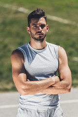handsome young man in sportswear looking at camera with crossed arms