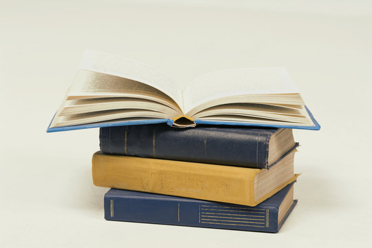 stack of books, a book on the top open pages, yellow, blue colors