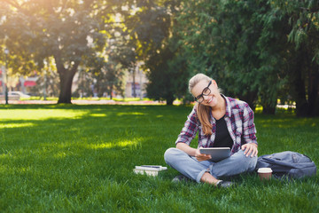 Happy young woman using digital tablet in park