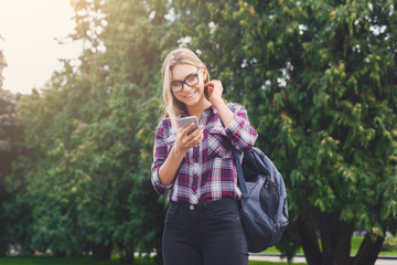 Student girl standing with mobile phone outdoors