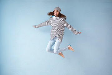 Obraz premium Jumping young woman with headphones on color background