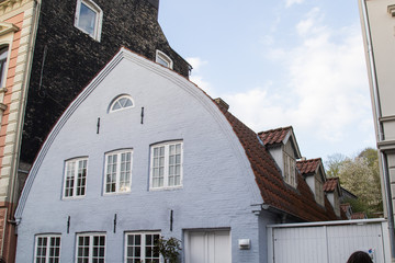 Tonnendach, Haus mit rotem Ziegeldach, hellblauer Fassade und weissen Sprossenfenster