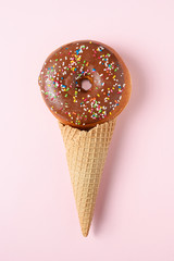Glazed donut with ice cream cone on pink pastel background. Flat lay. Creative concept.