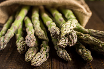 Fresh Asparagus in Juta Bag on Wooden Background