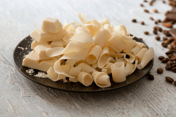 Plate with white chocolate curls on table