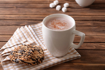 Cup of delicious cocoa drink with cookies on table