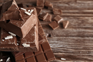 Pieces of chocolate on wooden background, closeup