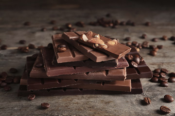 Chocolate bars with almonds and coffee beans on wooden background