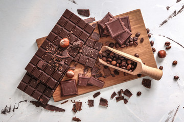 Tasty chocolate pieces and coffee beans on wooden board, top view