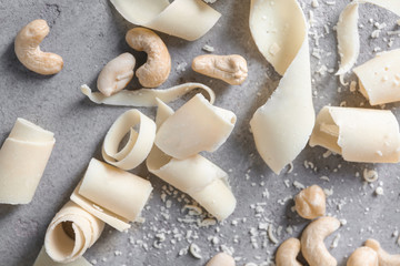 White chocolate curls and nuts on grey background