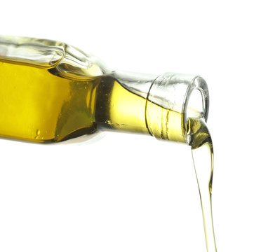 Pouring of olive oil from bottle on white background