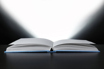 Open book with glowing on dark background