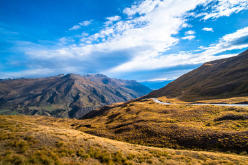 The beautiful road between Queenstown and Wanaka via Crown range. Grassland and beautiful landscape of rocky mountains.