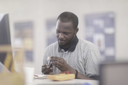Man sitting at a desk inspecting a tool