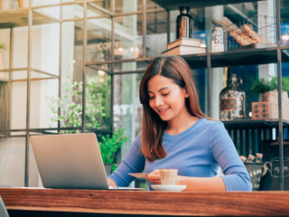 Asain woman working with laptop in coffee shop.