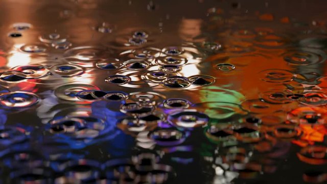 3D animation of the rain droplets in a street puddle with reflections of a city traffic