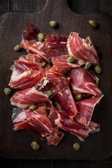 Traditional Spanish Jamon Serrano ham, Prosciutto Crudo, Parma ham, Italian antipasto, served with capers.