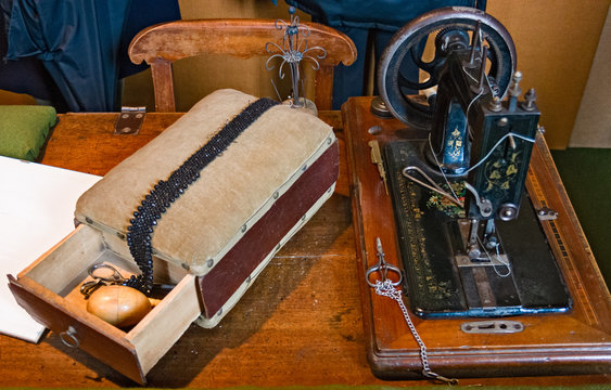 Antique sewing machine resting on a table and surrounded by other tailoring tools.