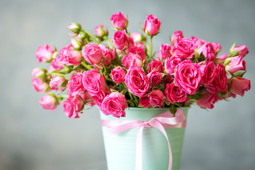 bouquet of pink roses in a mint-colored pot on a blurred background