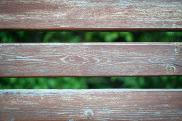 back bench close-up. the background of three wooden horizontal boards between which you can see the...
