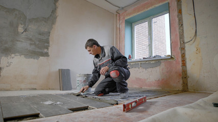 Construction worker using plastering tools renovating apartment house. Construction work starts.