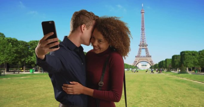 Happy multiethnic couple take a selfie near the Eiffel Tower, Caucasian male and African female take picture together on honeymoon in Paris, 4k