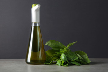 Bottle with olive oil and basil leaves on table