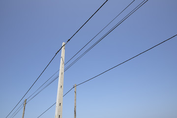 Three electricity poles and lines against a blue sky
