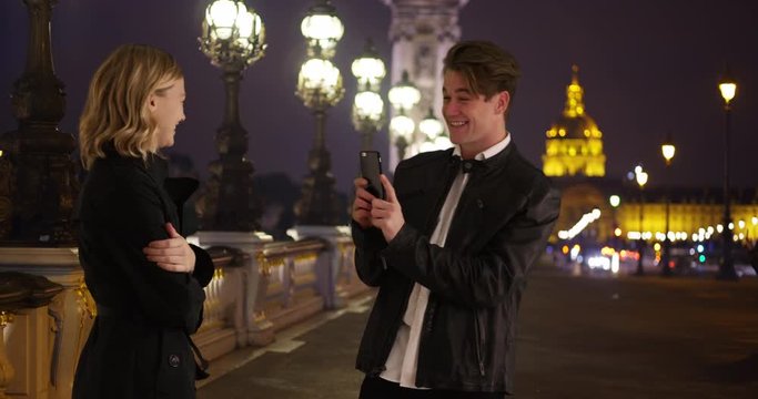 A man takes picture of his pretty girlfriend in Paris, Loving young couple standing on Pont Alexandre III Bridge in Paris, 4k