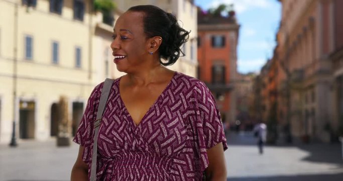 Happy senior black woman sightseeing on urban street in Rome, Mature African American woman exploring Rome, looking around at buildings and smiling, 4k