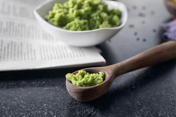 Spoon with delicious guacamole dip made of avocado on table