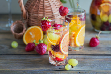 Homemade refreshing fruit sangria or punch with champagne, strawberries, oranges and grapes.