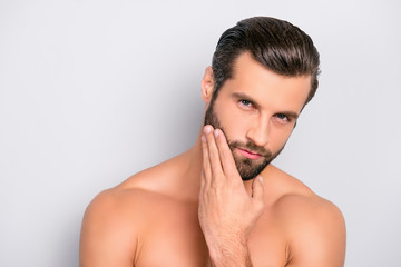 Attractive, brutal, modern, manly, virile, confident, dreamy, naked man touching his perfect, ideal face skin, holding hand on beard, cheek, looking at camera, isolated over gray background