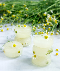 Ice cubes of chamomile tea and chamomile for cosmetic purposes on a background of a bouquet of daisies.