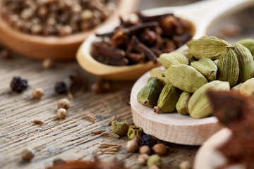 Colourful aromatic various spices for cooking on old wooden board, close-up, flat lay, shallow depth of field.
