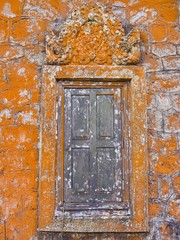 Beautiful bright orange moss on old stone wall and wooden window of the temple.