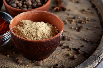Spices in ceramic bowls on the top of wooden barrel, close-up, selective focus.