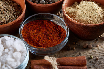 Spices in ceramic and glass bowls on the top of wooden barrel, close-up, selective focus.