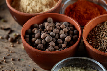 Spices in ceramic and glass bowls on the top of wooden barrel, close-up, selective focus.