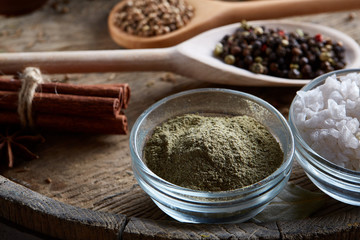 Various spices in wooden spoons and bowls and some salt on an old wooden barrel, top view, close-up, selective focus.