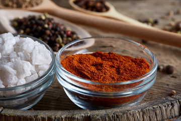 Various spices in wooden spoons and bowls and some salt on an old wooden barrel, top view, close-up, selective focus.