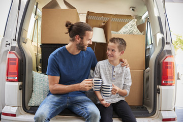Father And Son Take A Break In Back Of Removal Van On Moving Day