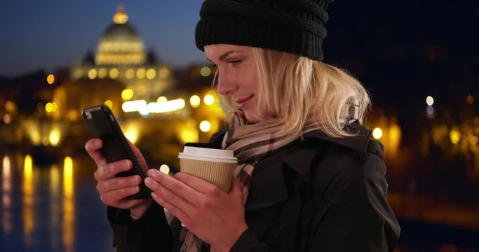 Traveling Caucasian young lady on phone outside in Rome, Italy in the evening, Young white woman in her 30s using smartphone outside while on vacation in Rome, 4k