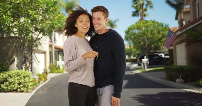 Portrait of young married couple holding keys to new house, Playful husband carries his wife down suburban street, 4k