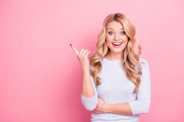 Portrait with empty place of astonished excited creative girl with modern hairdo pointing to copyspace looking at camera isolated on pink background. Choice recommend concept