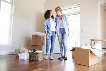 Female Friends Standing In Lounge Of New Home On Moving Day